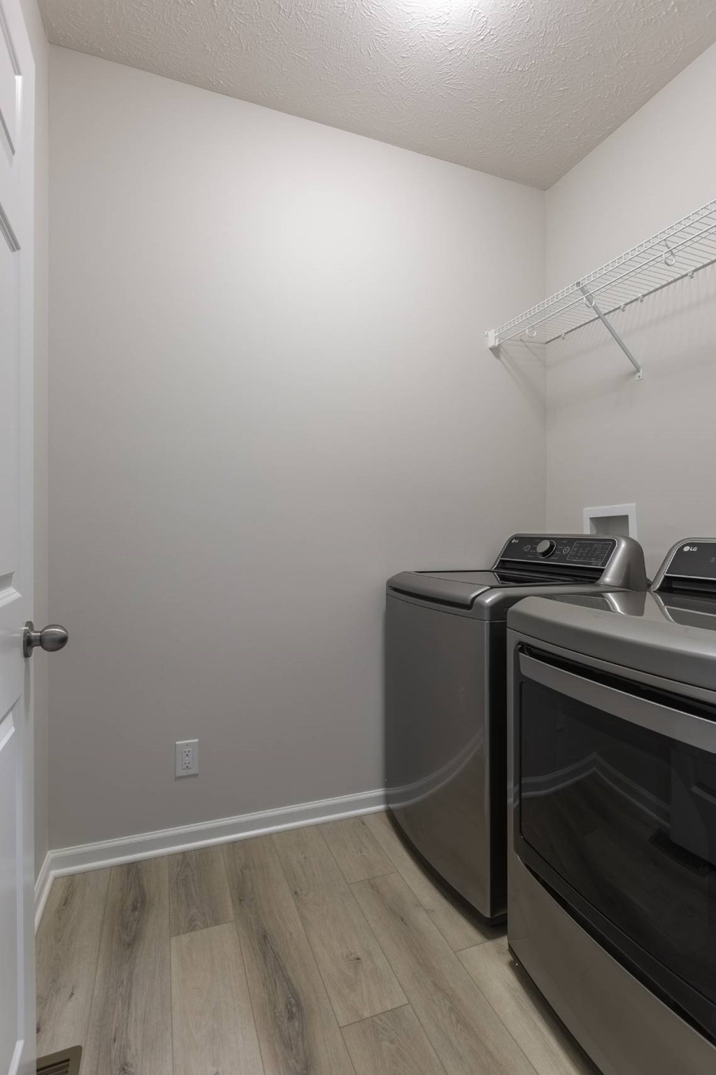 A kitchen with a white door, a wall-mounted oven, and a wall-mounted toaster.