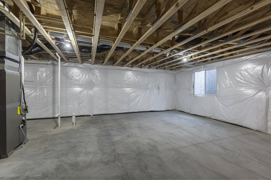 A room with a white ceiling and walls, covered in plastic, with a door on the left.