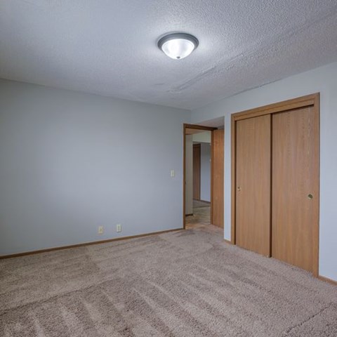 Room with tan carpet and brown closet doors.