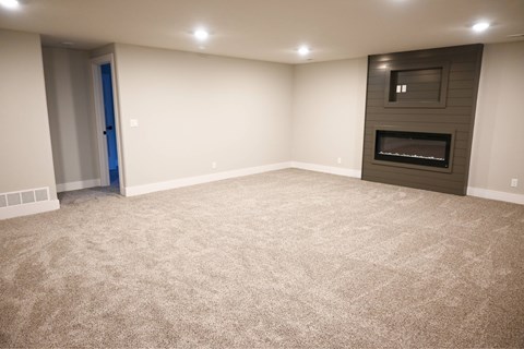 A spacious room with a carpeted floor and a fireplace.