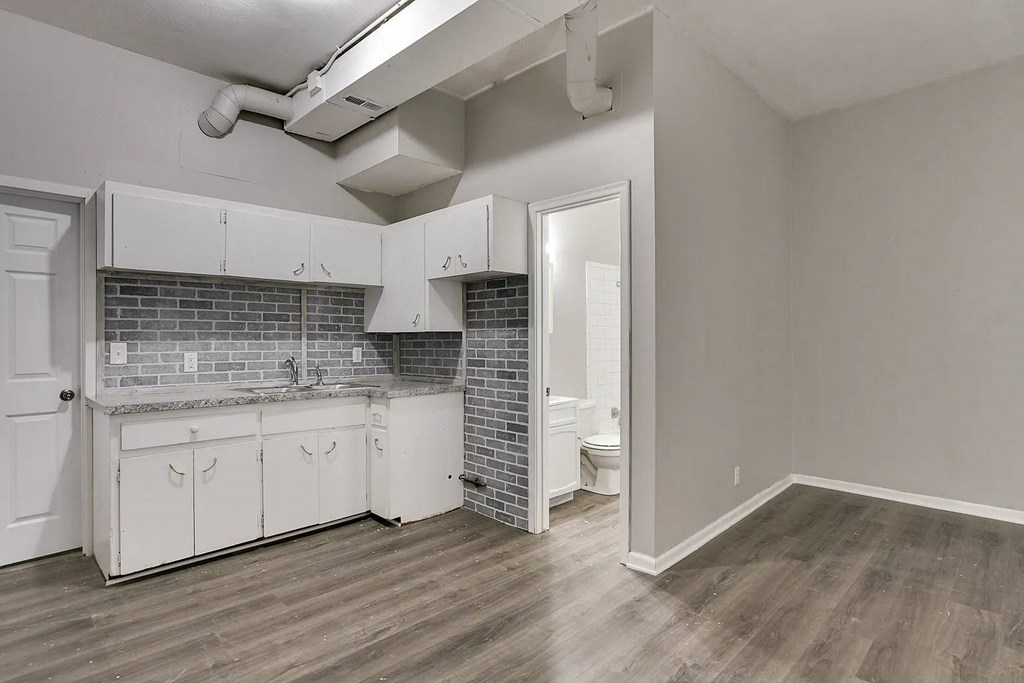 A kitchen with white cabinets and a brick backsplash.