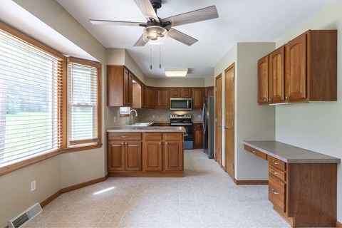 A kitchen with wooden cabinets and a ceiling fan.