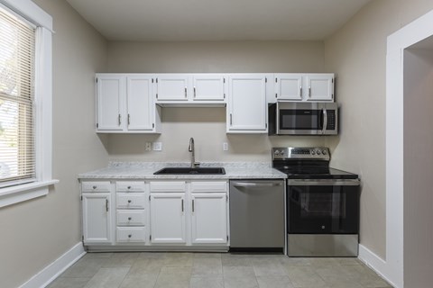 A kitchen with white cabinets and appliances.