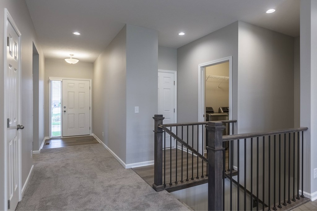 A hallway with a black railing and a white door.
