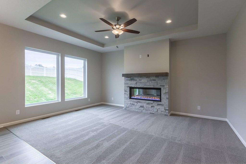A spacious room with a fireplace and a ceiling fan.