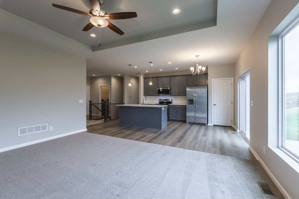 A spacious kitchen and living room with a ceiling fan and hardwood floors.