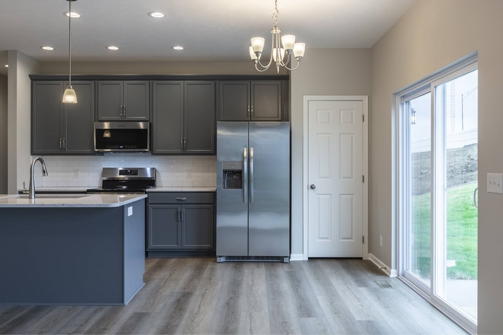 A kitchen with a refrigerator, sink, and cabinets.