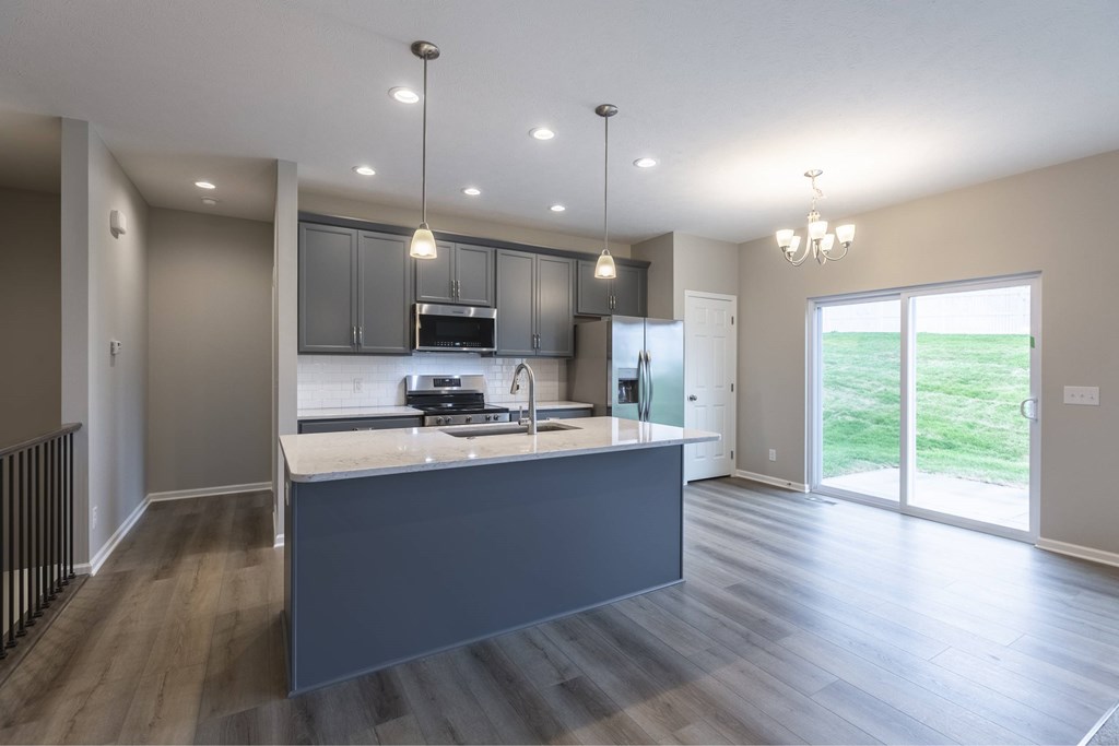 A modern kitchen with a large island and a view of the backyard.