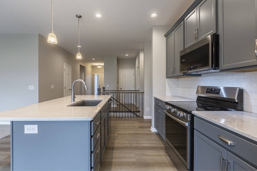 A modern kitchen with a sink, stove, and cabinets.