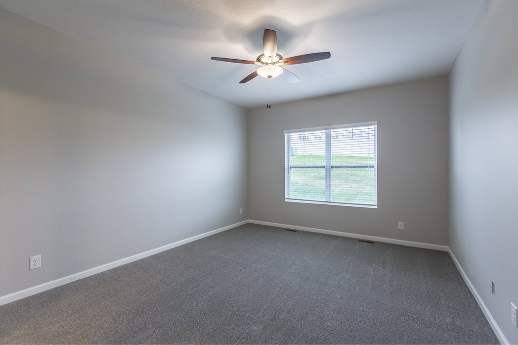 A room with a ceiling fan and a window.