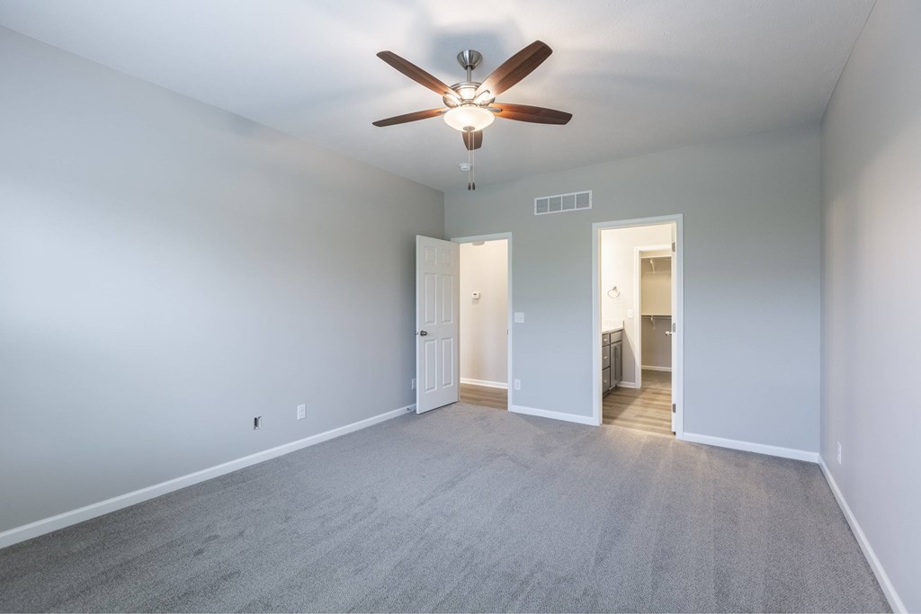 A room with a ceiling fan and carpeted floor.