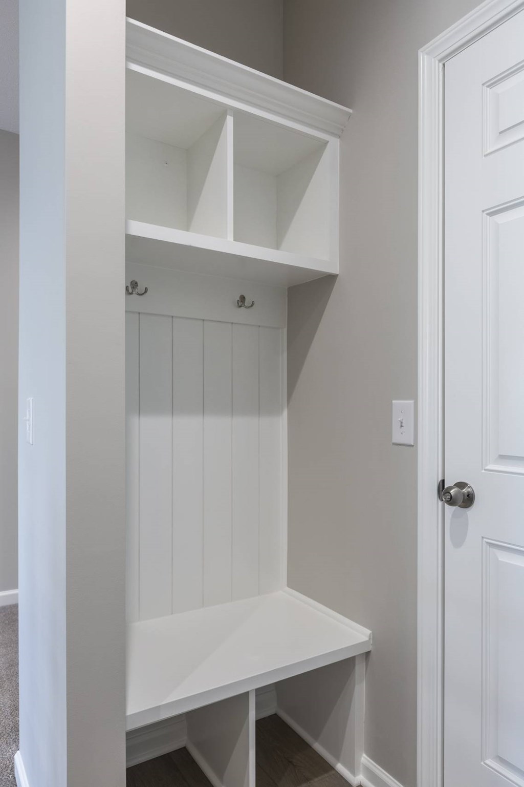 A white built in bench and shelves in a room.