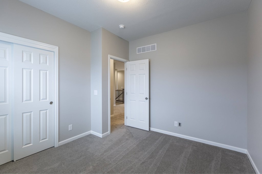 A room with a white door and a grey carpet.