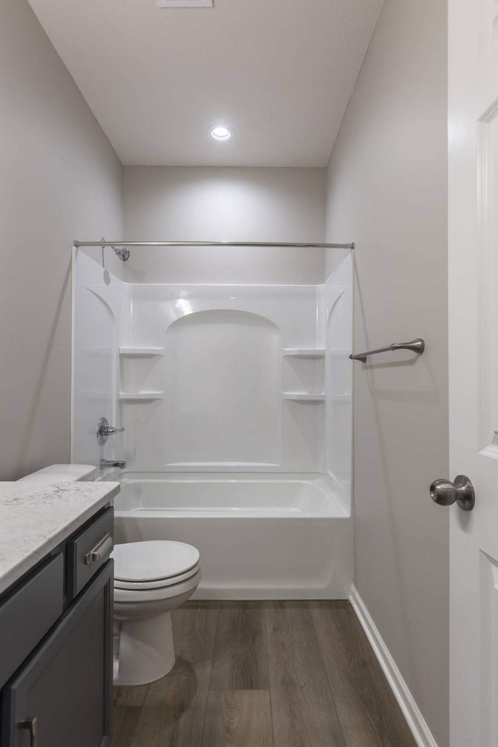 A white toilet sits in a small bathroom with a walk-in shower.