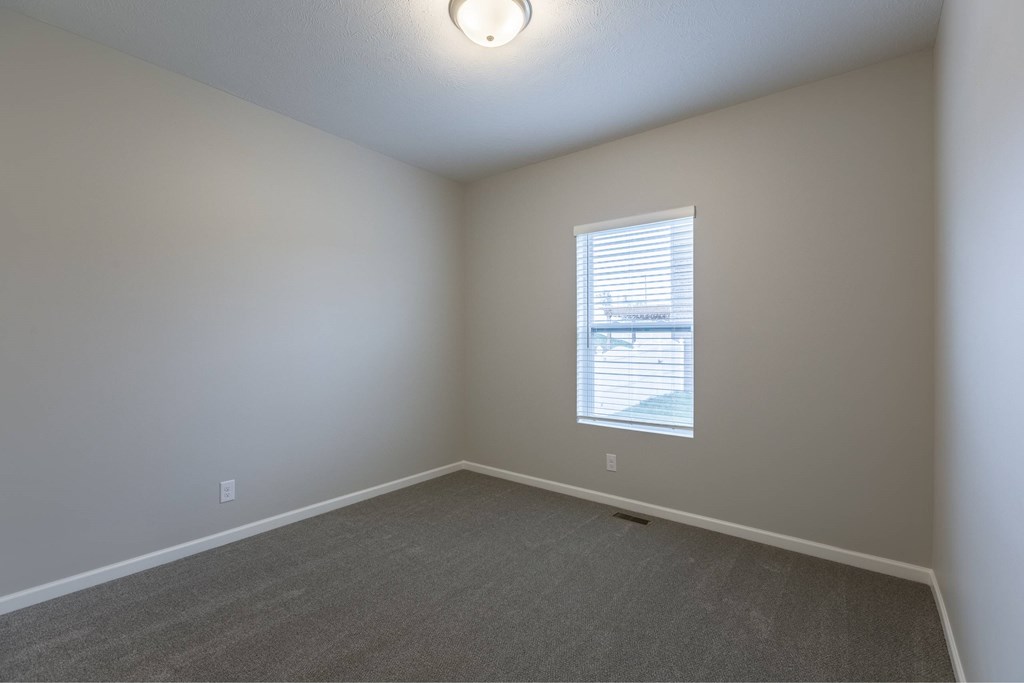 A room with a window and carpeted floor.