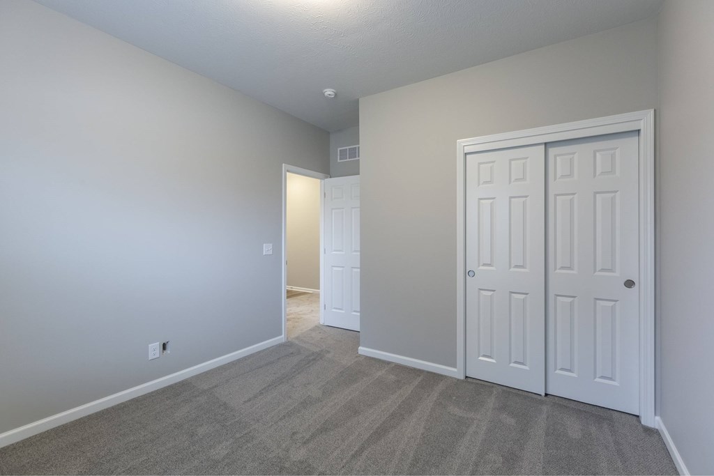 A room with a carpeted floor and a white door.