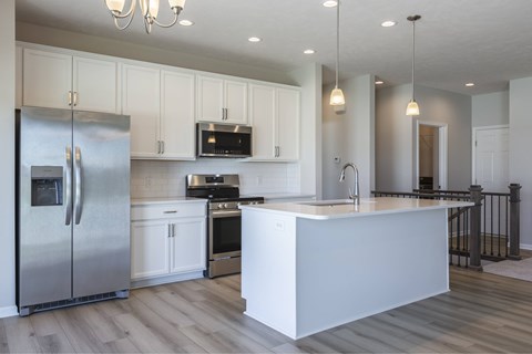 A modern kitchen with a stainless steel refrigerator and white cabinets.