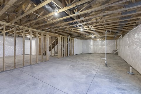 A spacious unfinished room with wooden beams and insulation on the walls.
