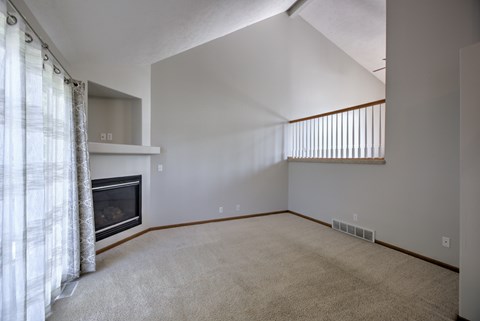 A living room with a fireplace and carpeted floor.