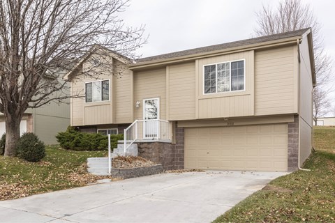 A beige house with a white door and windows.