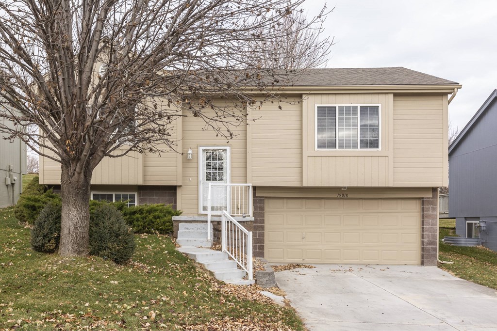 A beige house with a white door and a small porch.
