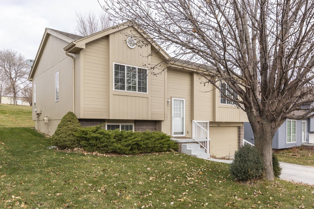 A beige house with a white door and windows.