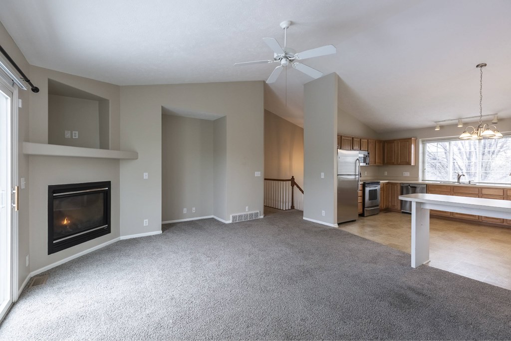 A spacious living room with a fireplace and a ceiling fan.