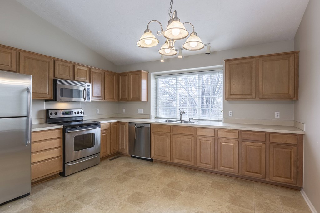 A kitchen with wooden cabinets and a stainless steel refrigerator.