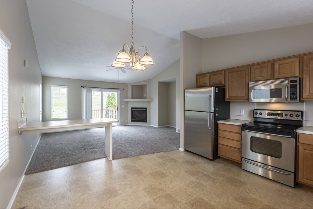 A kitchen with a stove, refrigerator, and microwave.