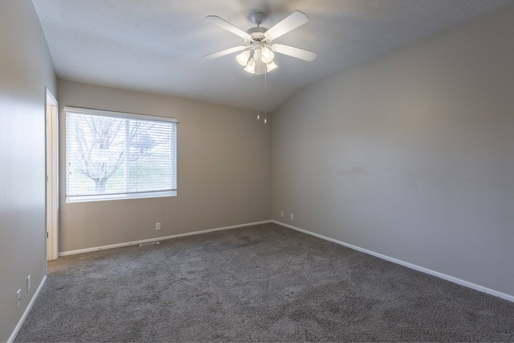 A room with a ceiling fan and carpeted floor.