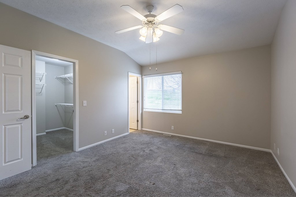 A room with a ceiling fan and a door leading to a bathroom.