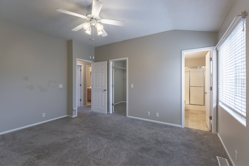 A room with a ceiling fan and carpeted floor.
