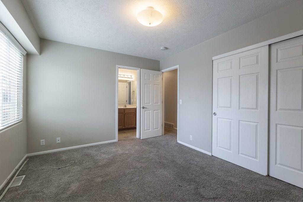 A room with white doors and carpeted floor.