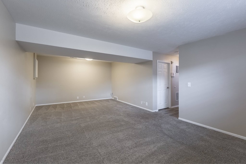 A spacious room with a carpeted floor and white walls.