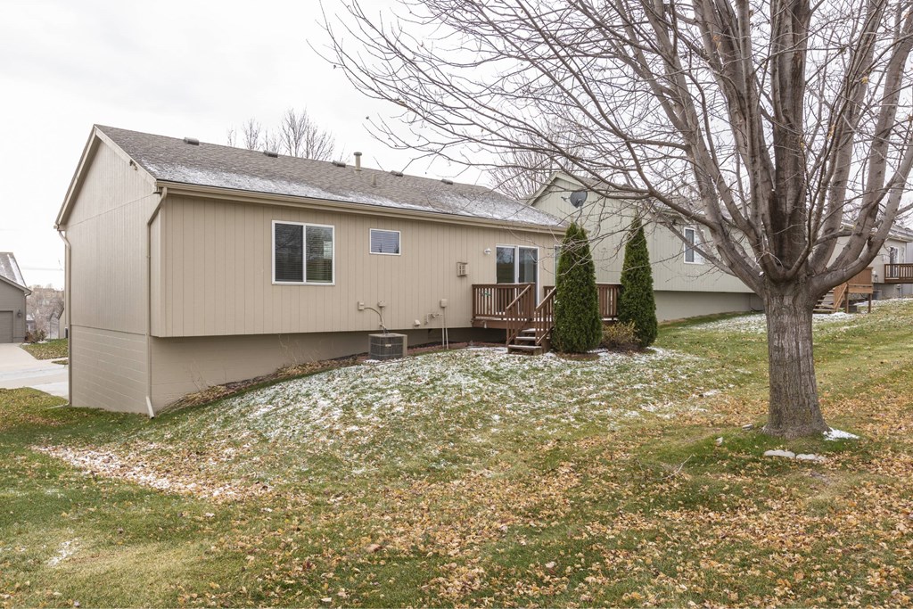 A house with a grey roof and a tree in front of it.