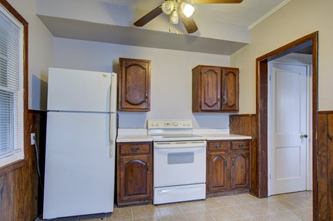 A white refrigerator is in a kitchen with wooden cabinets.