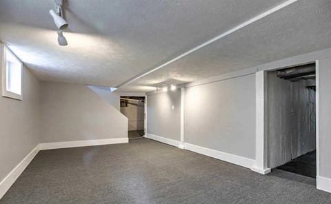 A room with a ceiling fan and a doorway leading to another room.