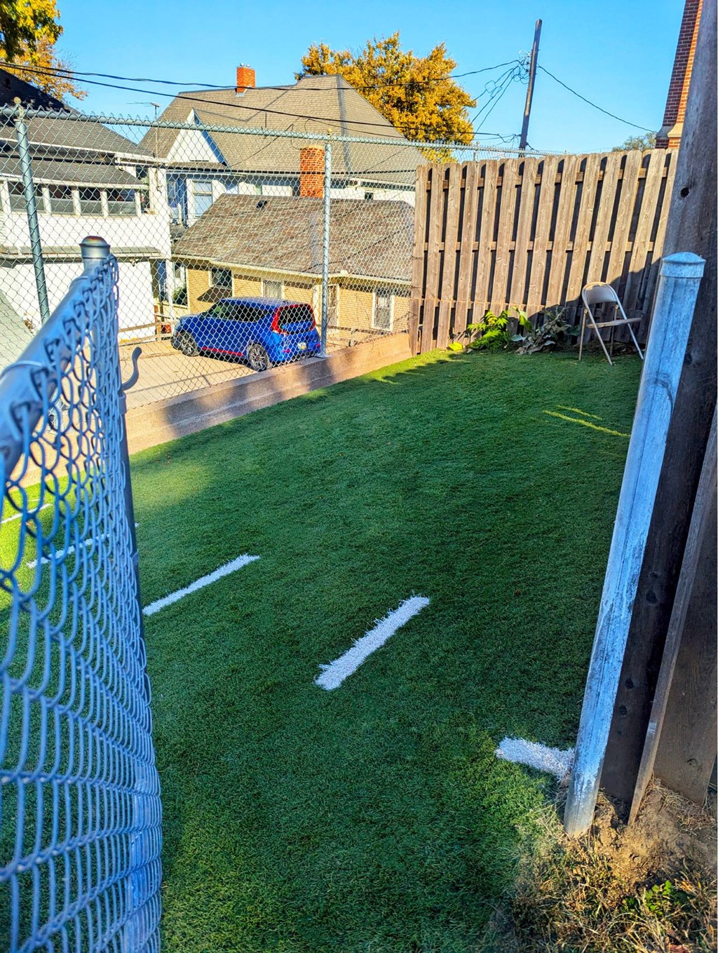 A blue car is parked in a driveway next to a house.