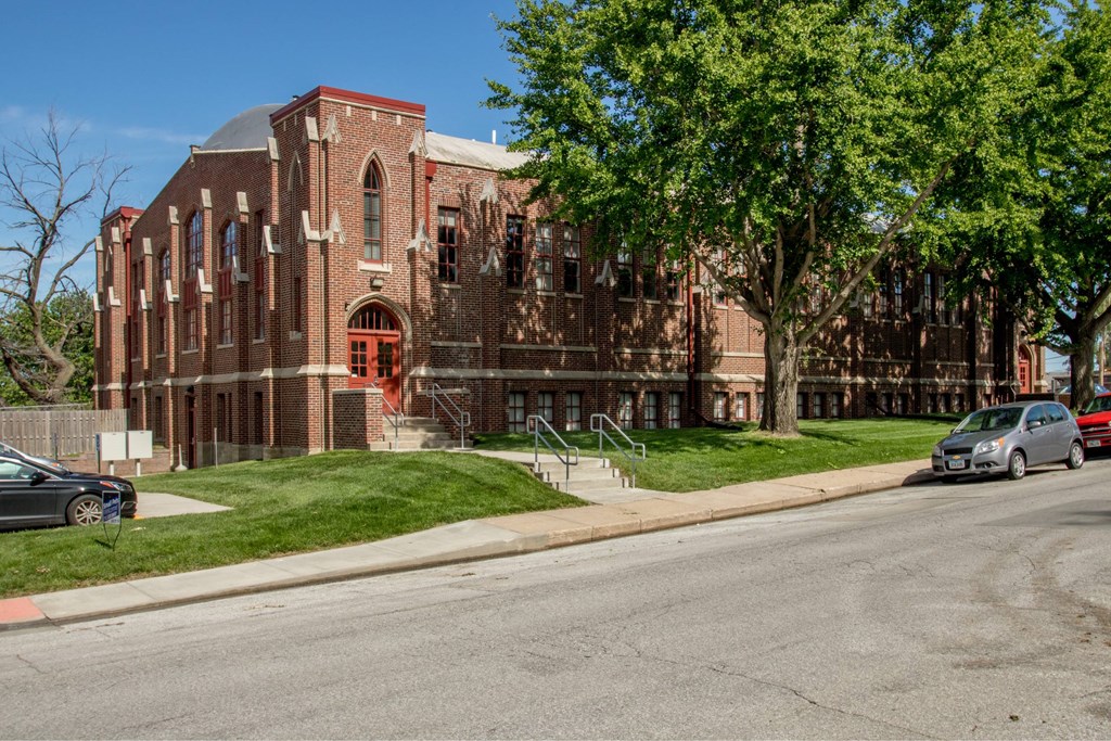 A red brick building with a green tree in front.
