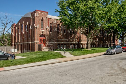 A red brick building with a green tree in front.