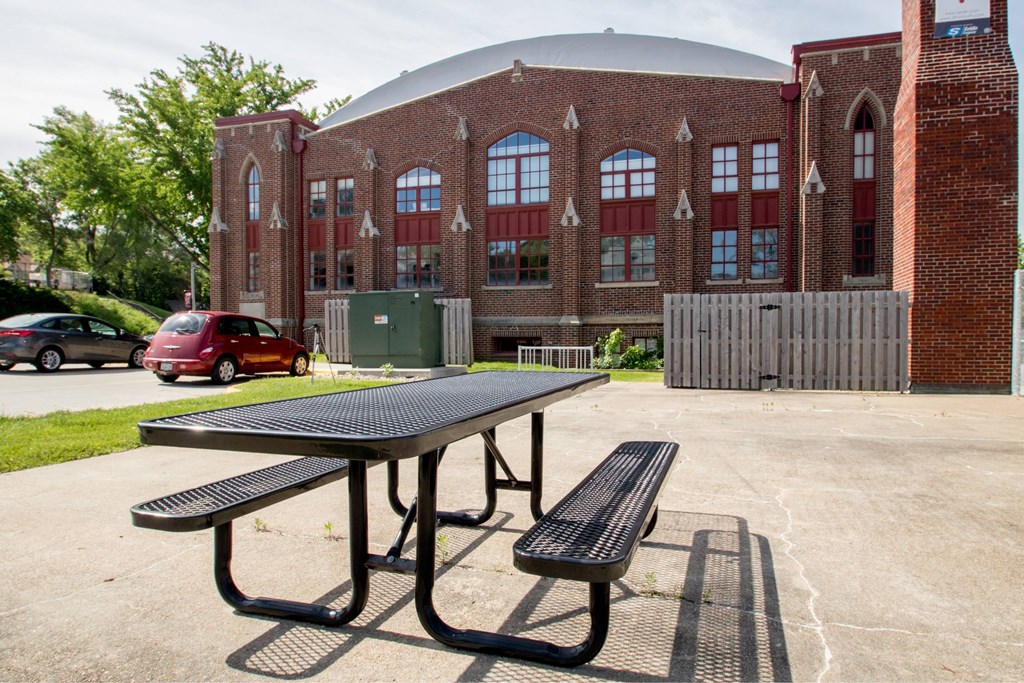 A picnic table is in front of a brick building.