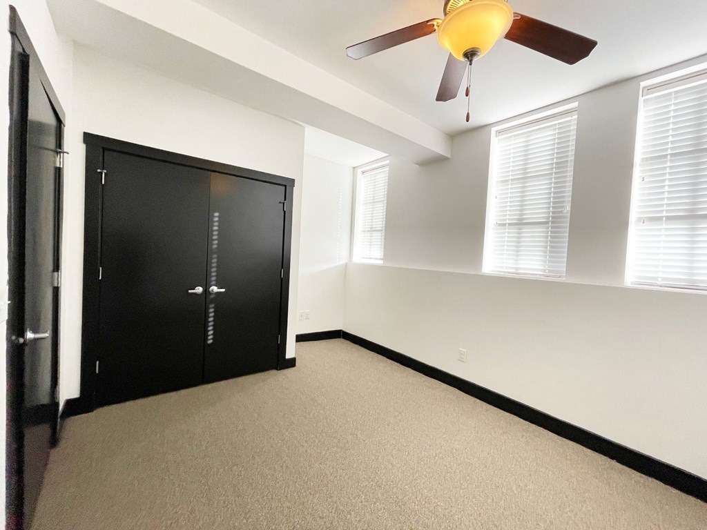 A room with a ceiling fan and a black wardrobe.