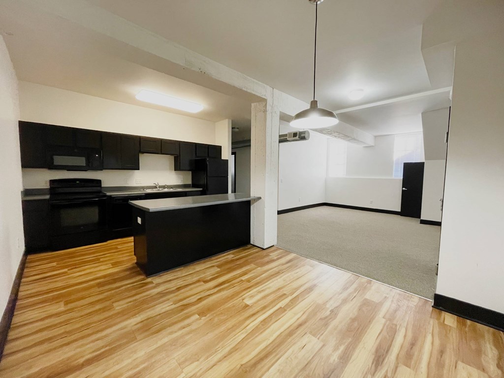 A kitchen with black cabinets and a wooden floor.