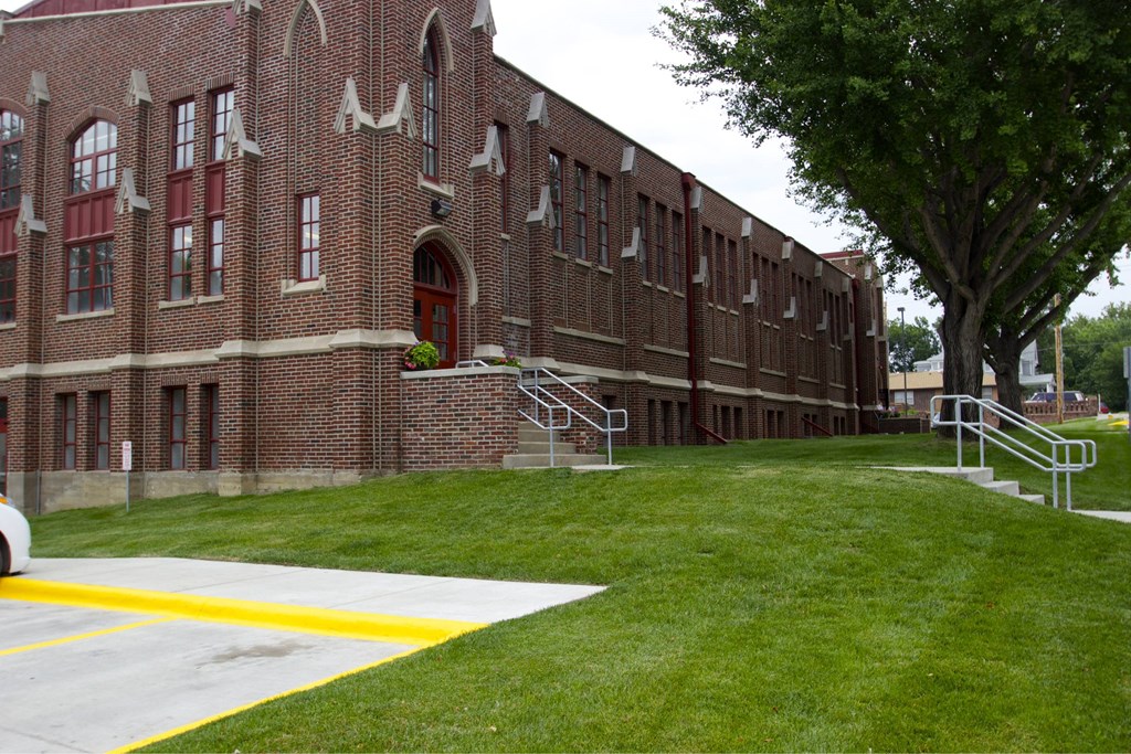 A red brick building with a tree in front.
