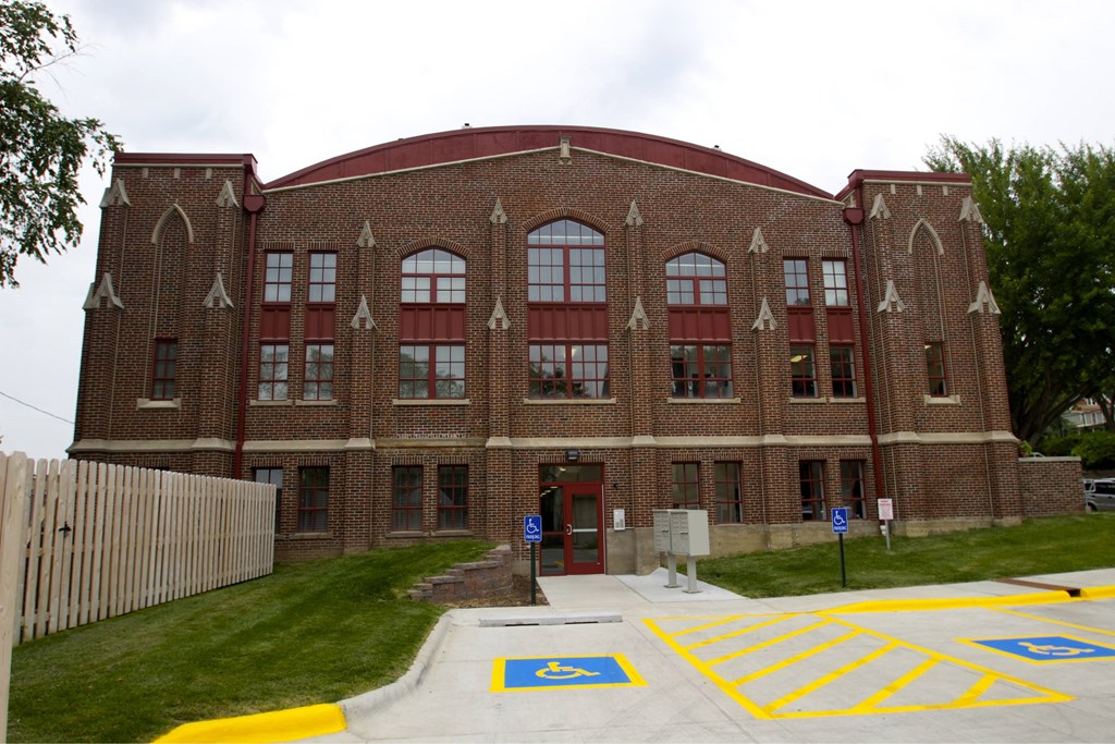 A red brick building with a red roof and a parking lot in front.