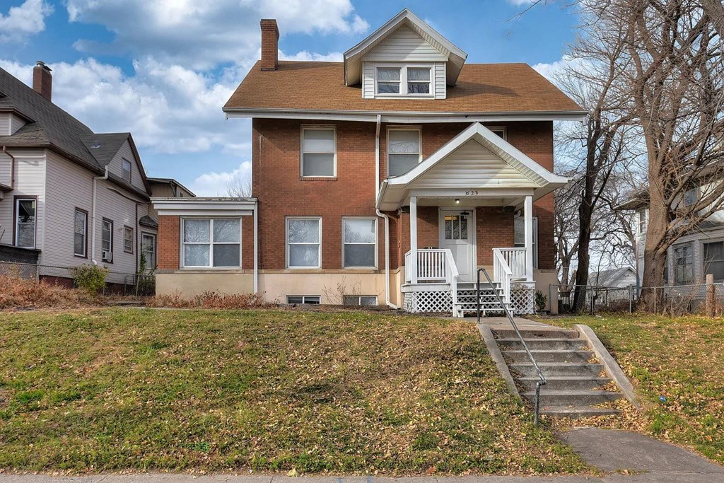 A house with a brown roof and a white porch.