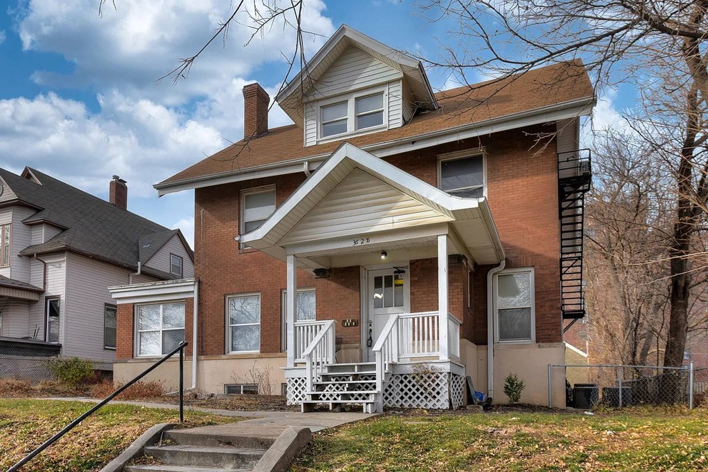 A two-story house with a front porch and a staircase leading to the second floor.