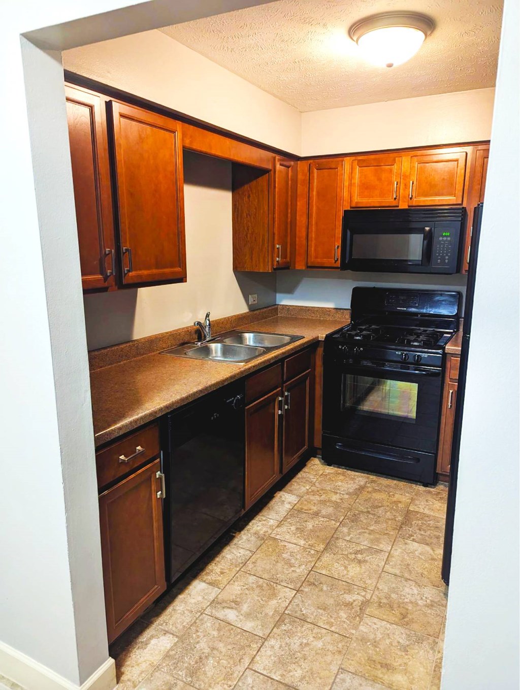A kitchen with black appliances and brown cabinets.