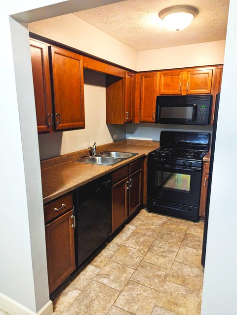 A kitchen with black appliances and brown cabinets.