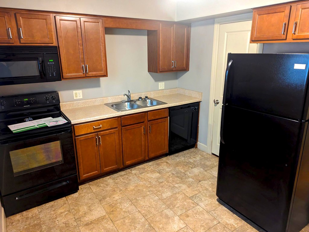 A kitchen with black appliances and wooden cabinets.